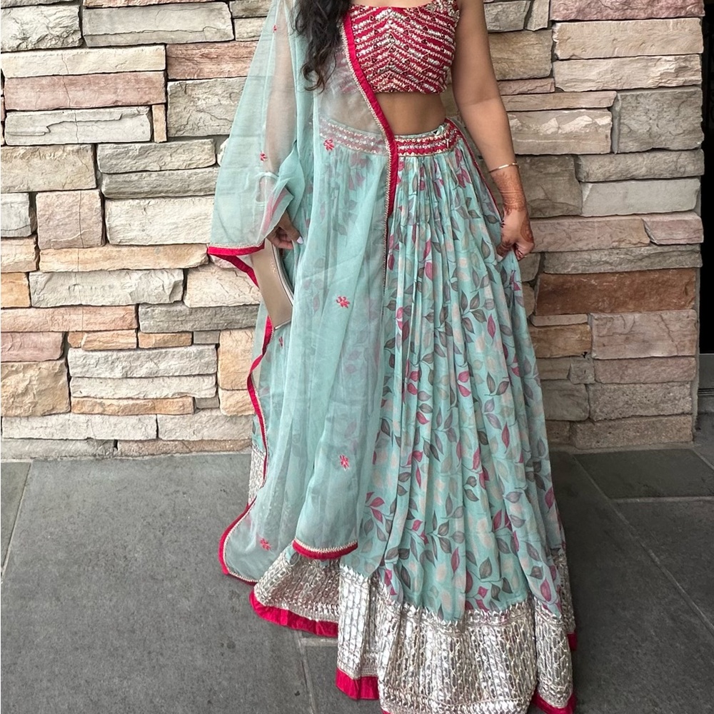 A beautiful turquoise green lehenga with a red blouse with gorgeous details.